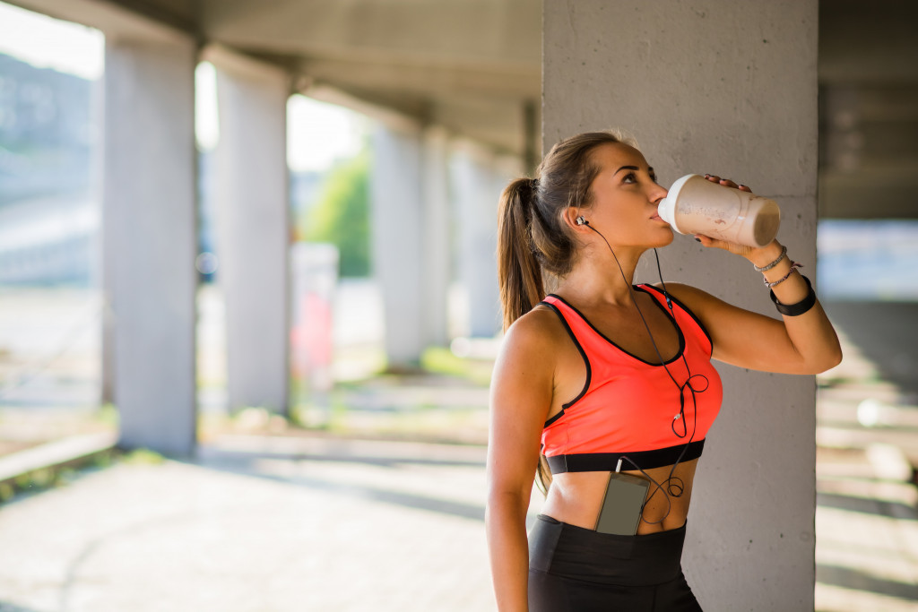 A woman wearing workout clothes drinking 