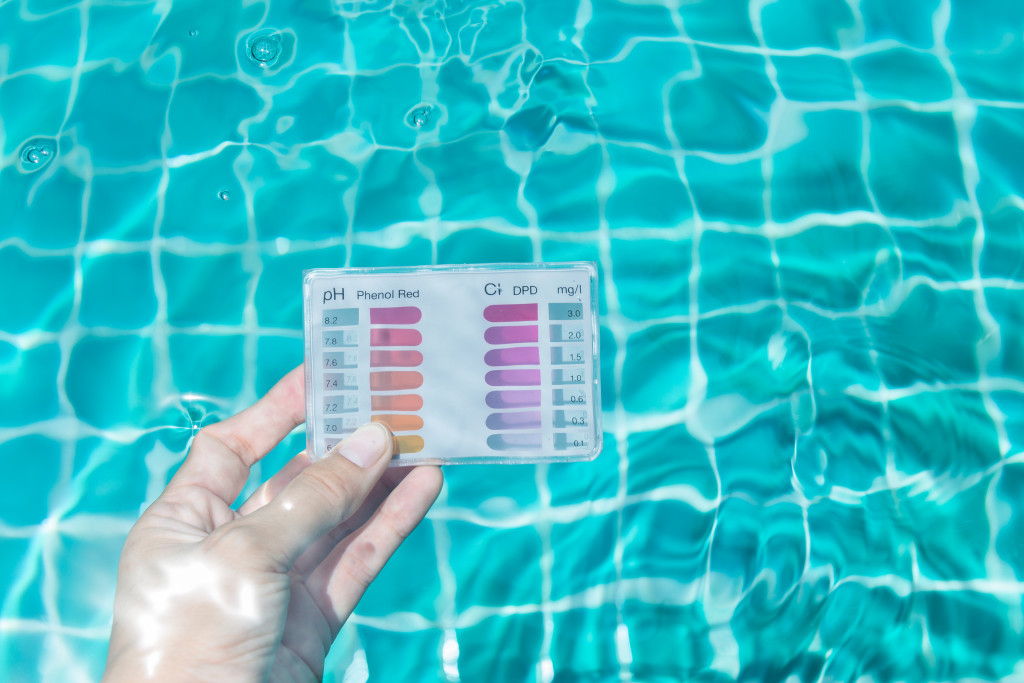 Someone submerging a pH testing kit in a swimming pool