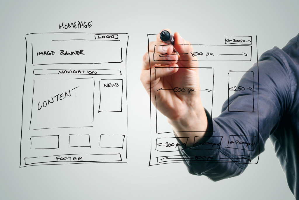 A designer drawing a web site concept on a glass board using a market